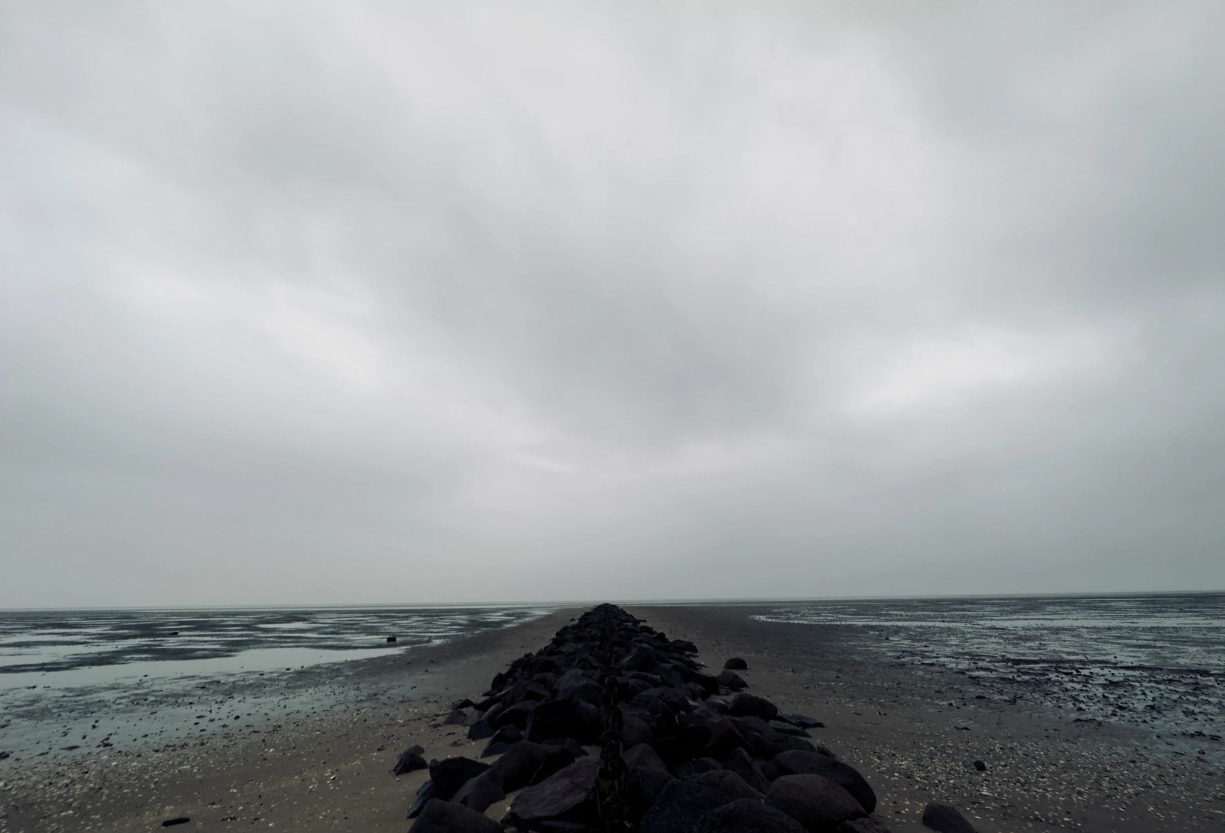 May Gil Photography - the photo shows a rock groyne structure (breakwater) that extends symmetrically into the distance from the center of the viewer's perspective